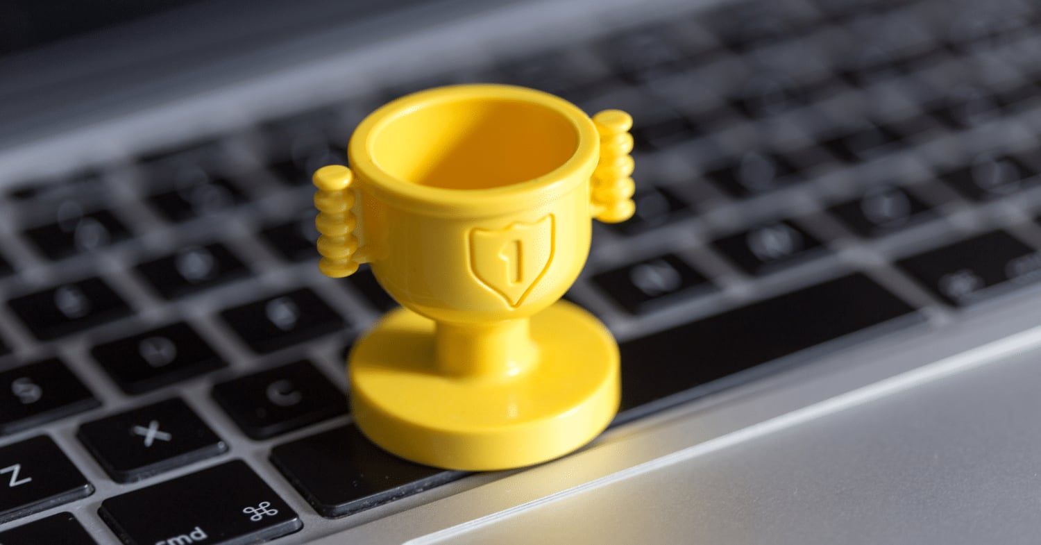 Kleiner gelber Pokal mit der Ziffer 1 auf der Tastatur eines silbernen Laptops
