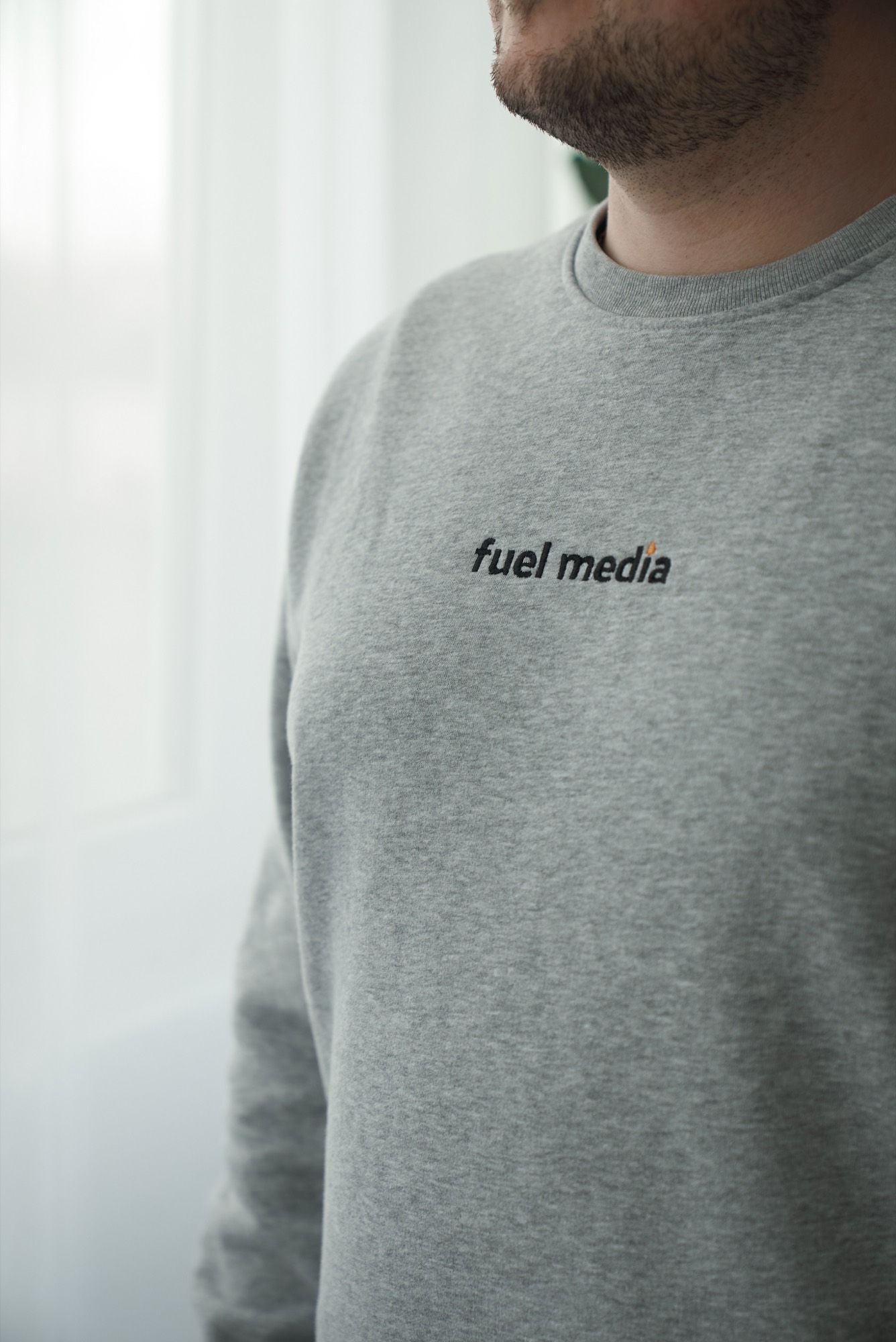 Grauer Pullover mit dem Schriftzug fuel media