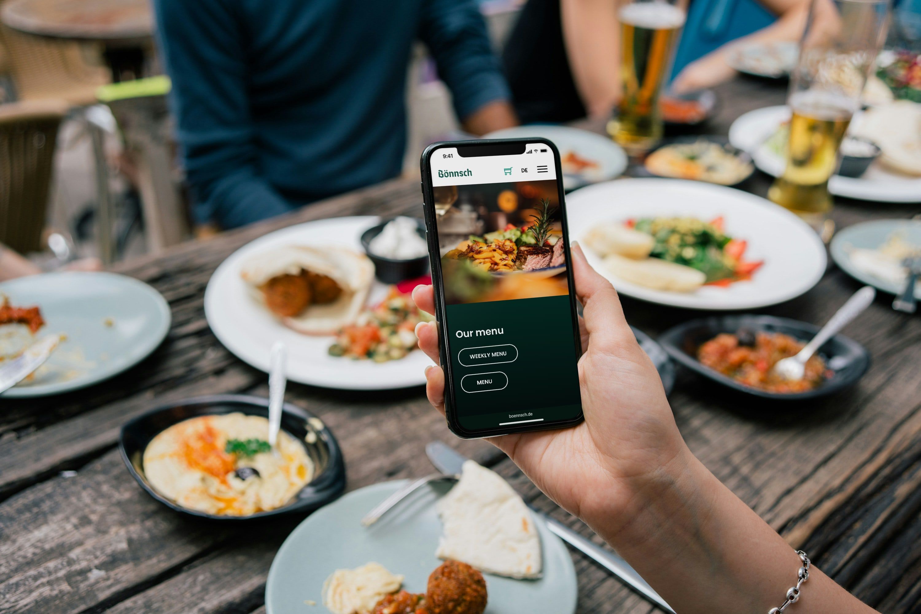 Englische Speisekarten-Seite von boennsch.de auf einem Smartphone am gedeckten Tisch