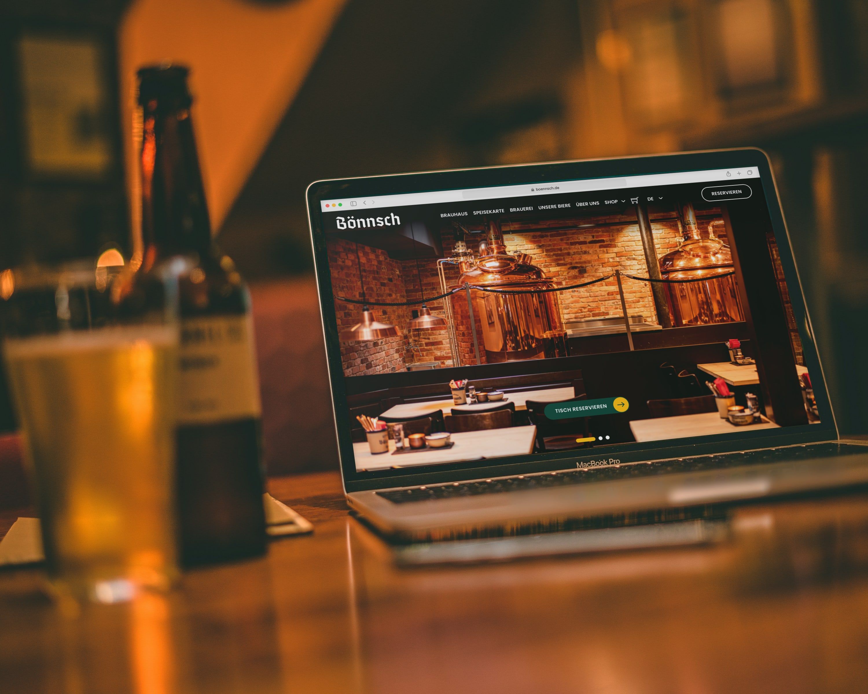 Neue Startseite von boennsch.de auf einem Laptop, daneben Bierflasche und Glas auf dem Tresen